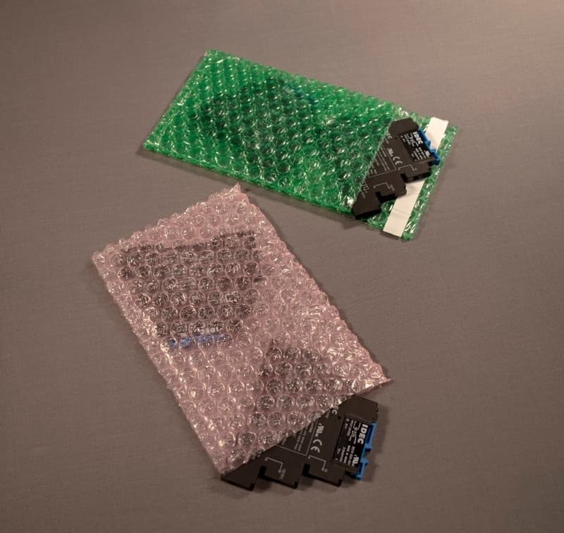 Componentes electrónicos protegidos por bolsas de burbuja ESD de PREMCO en colores verde y rosa, asegurando protección contra descargas electrostáticas.