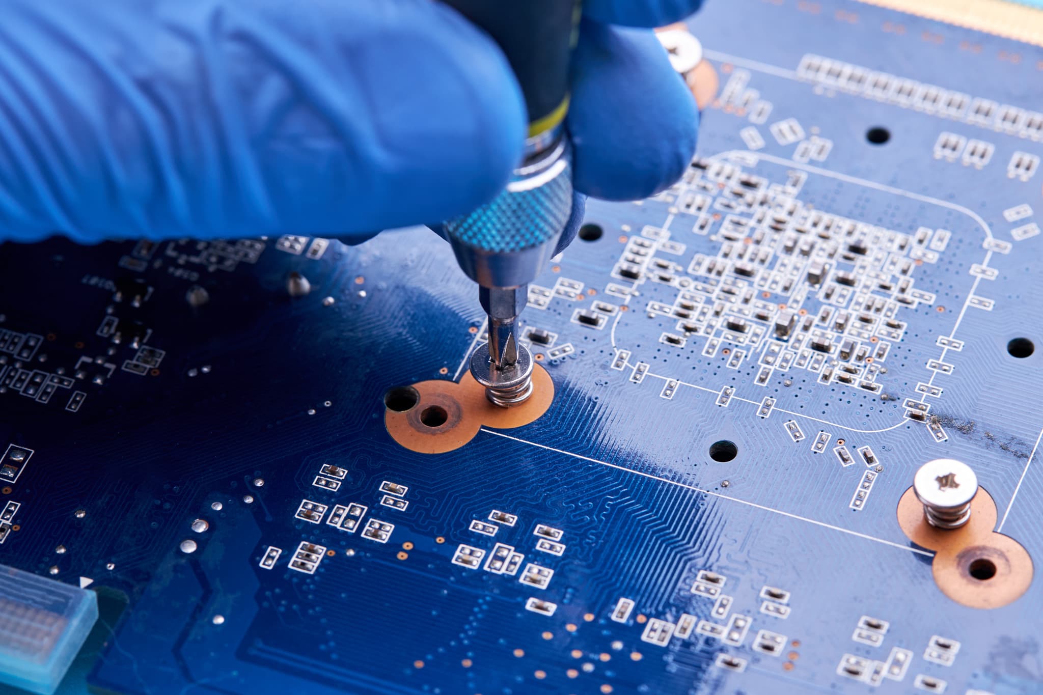 Manos con guantes ESD atornillando un componente electrónico