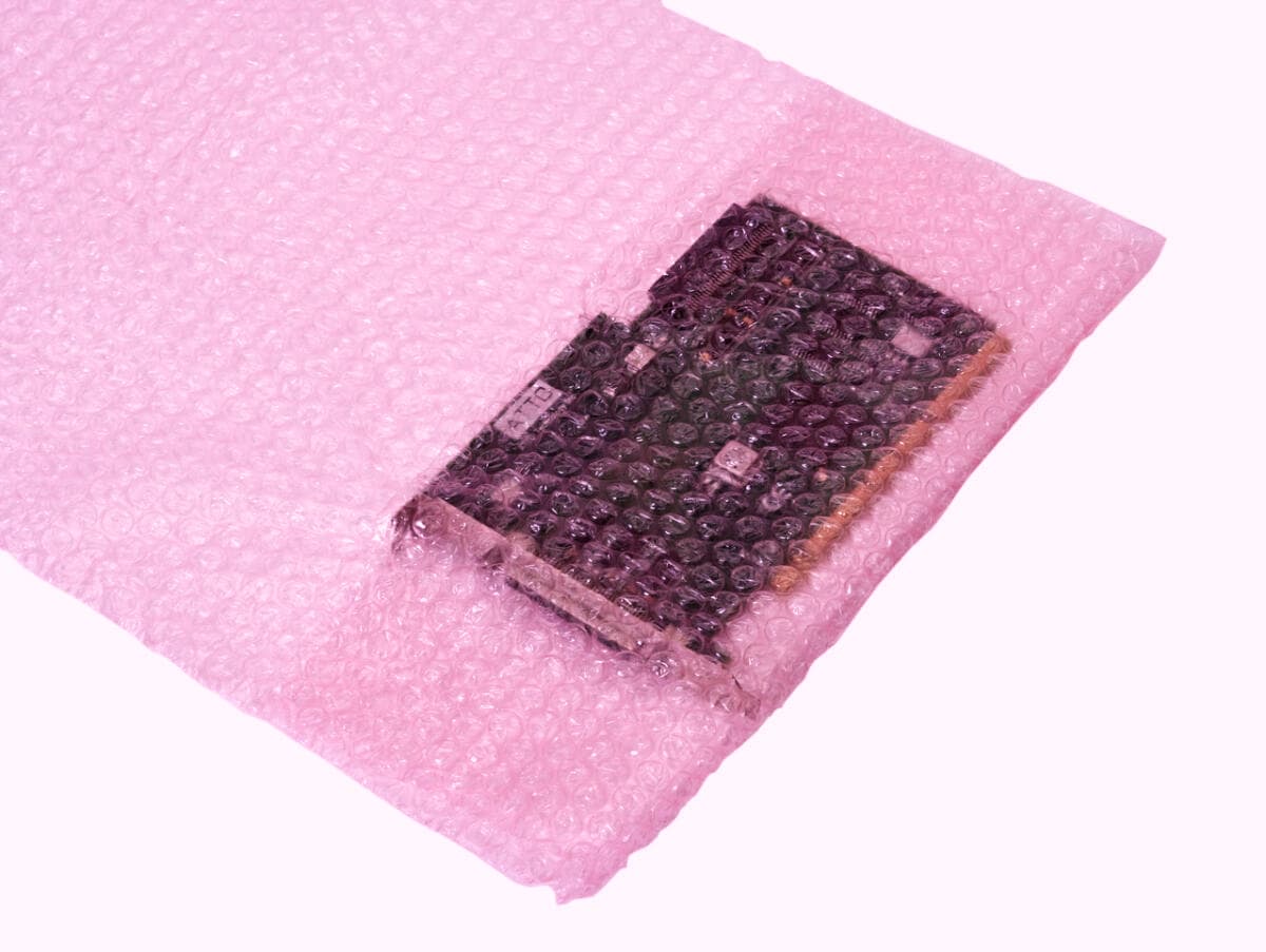 Disco duro envuelto en bolsa de burbuja ESD rosa de PREMCO para protección contra impactos y descargas electrostáticas.